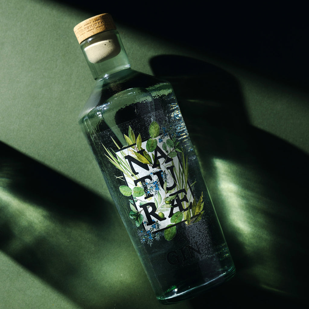 Bottiglia di Naturae Gin Herbarium, distilled gin artigianale con ginepro, menta, lemongrass e foglie d’ulivo, made in Italy. Riflessi Verdi 